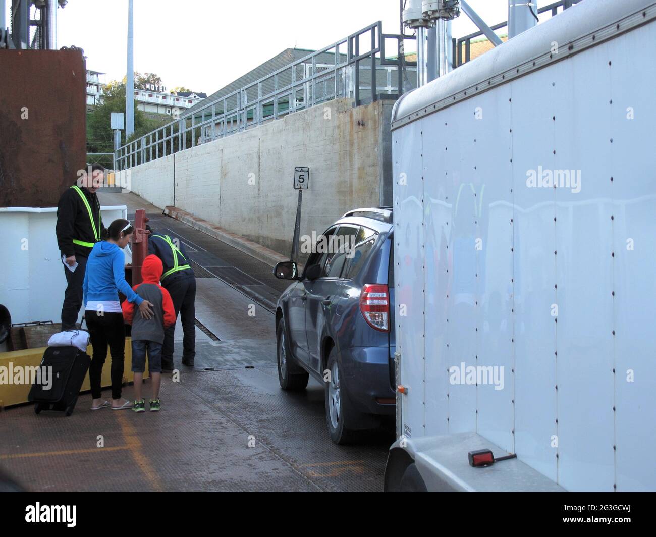 Car with trailer and people disembarking from a ferry boat Stock Photo