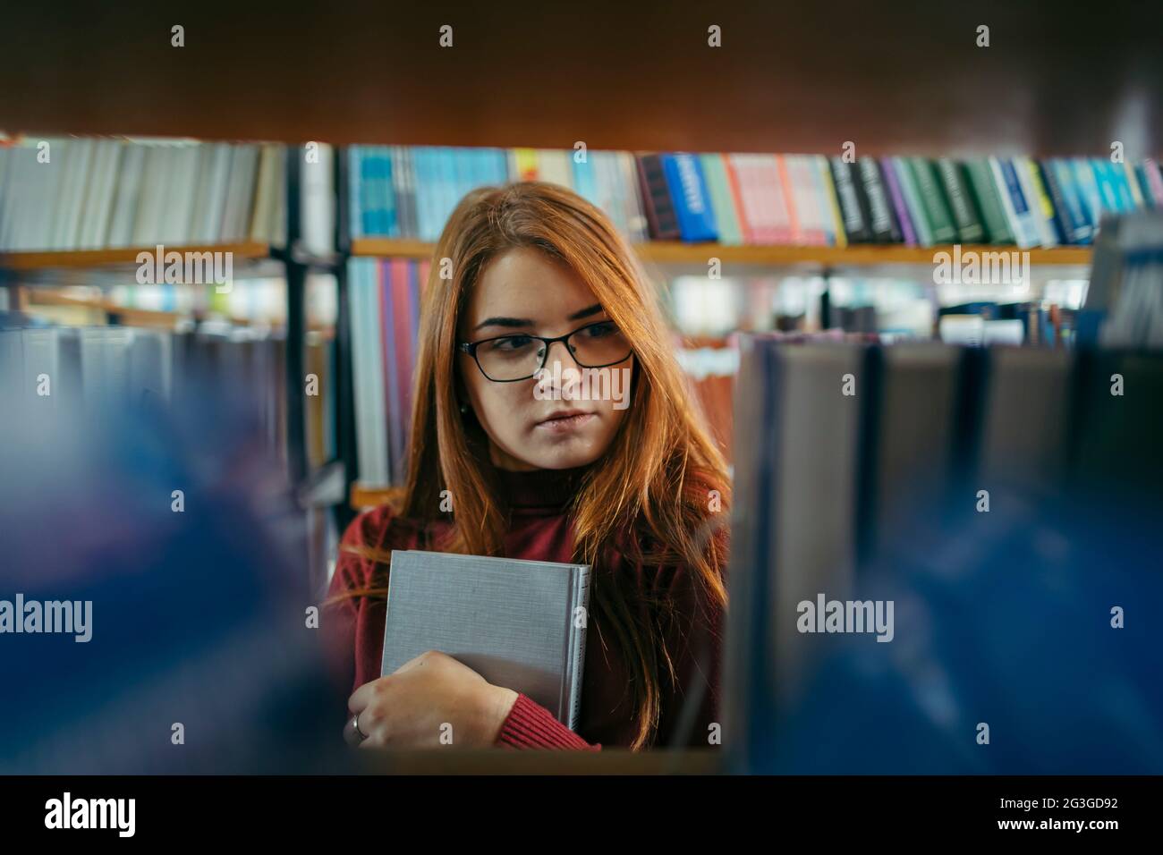 A girl holding a book shelf, student in the library Stock Photo - Alamy