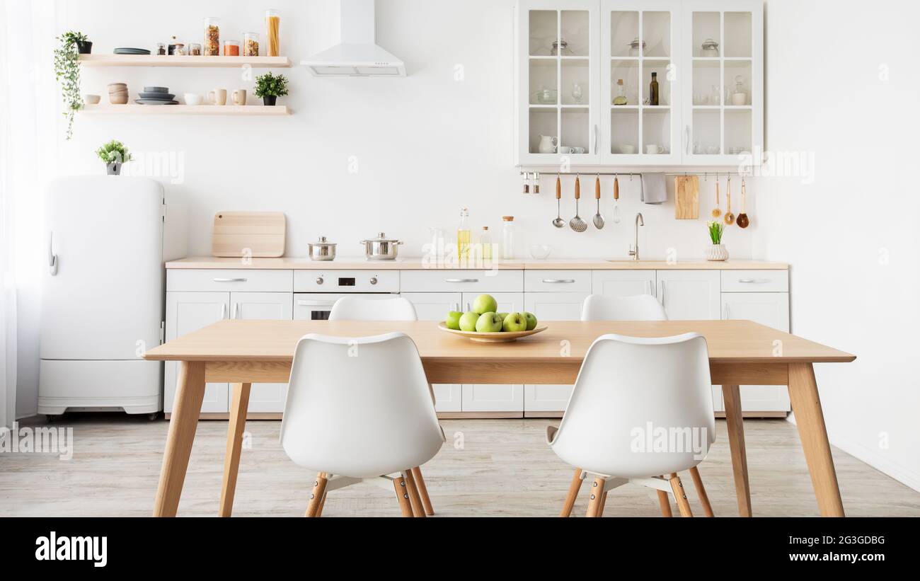Minimalist design of kitchen. Plate of apples on table, kitchenware and utensils on furniture, panorama Stock Photo