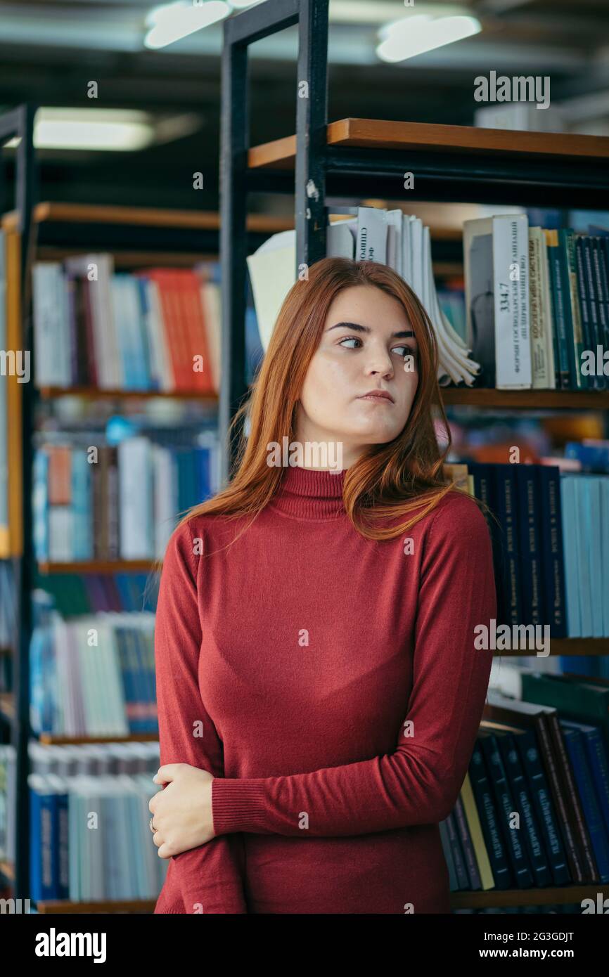 A girl holding a book shelf, student in the library Stock Photo - Alamy
