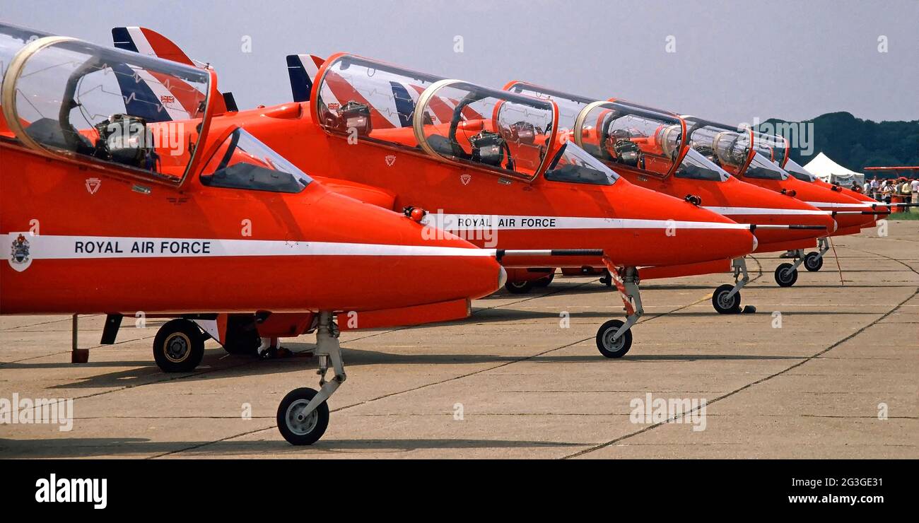 Close up 1980s archive view row of five Red Arrows Royal Air force RAF aerobatics flying display team jet engine red white and blue BAE Hawk trainer military airplane neatly lined up with open cockpit canopy on concrete hard standing at Air Tattoo taking place on North Weald Airfield an archival image near Epping in 80s Essex England UK Stock Photo