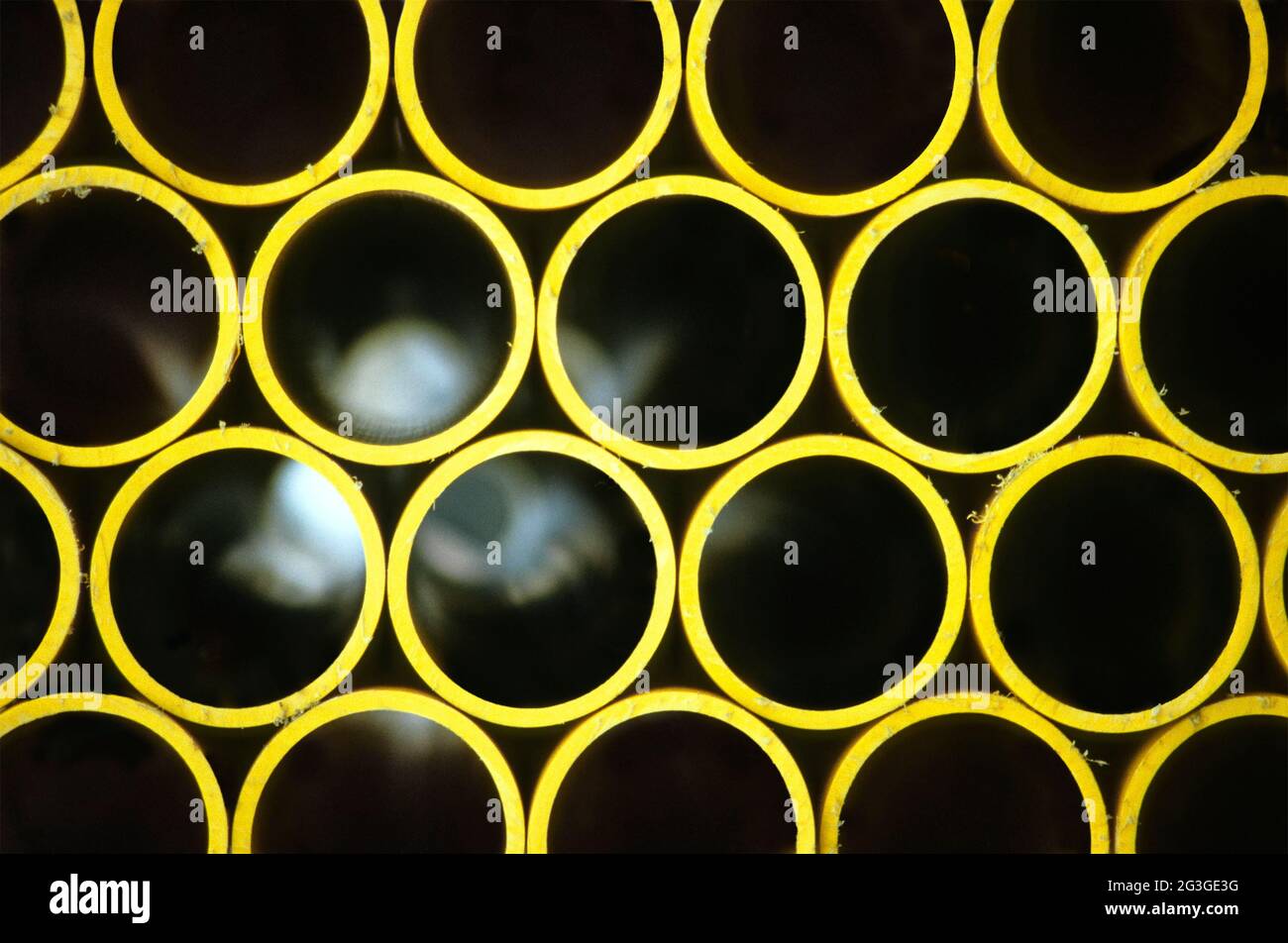 Archive 1986 close up view of part of a stack of dirty ends & burs on round plastic gas pipes showing concept of light at the end of the tunnel on street pavement before burying in trench to replace old gas main supply creating an abstract background image of yellow round regular symmetrical geometric pattern of rounded shapes joined up by circles in Essex England UK Stock Photo