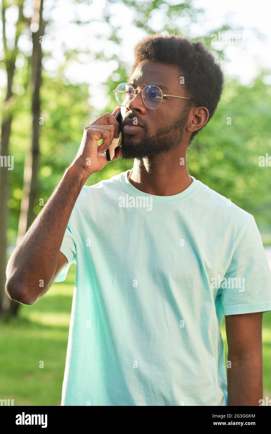 African young man talking on mobile phone while standing outdoors Stock Photo