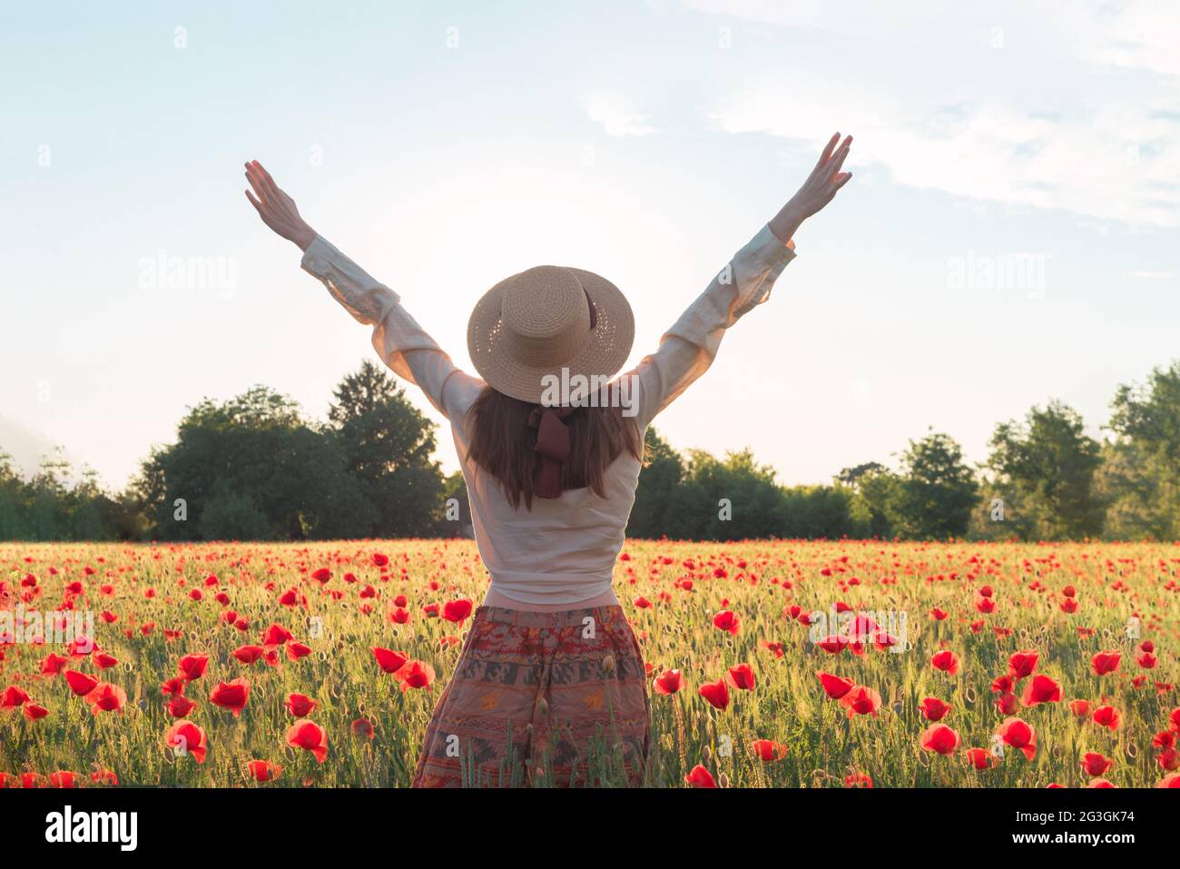 Young woman dancing on poppy field from back Stock Photo