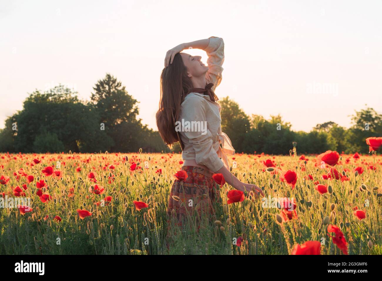 Young woman dancing on the poppy field Stock Photo