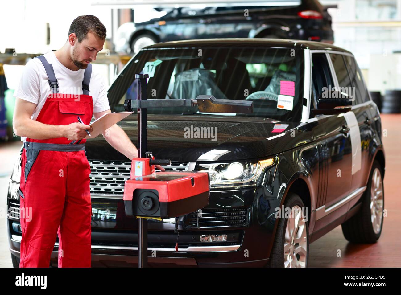 car repair shop worker checks and adjusts the headlights of a car's