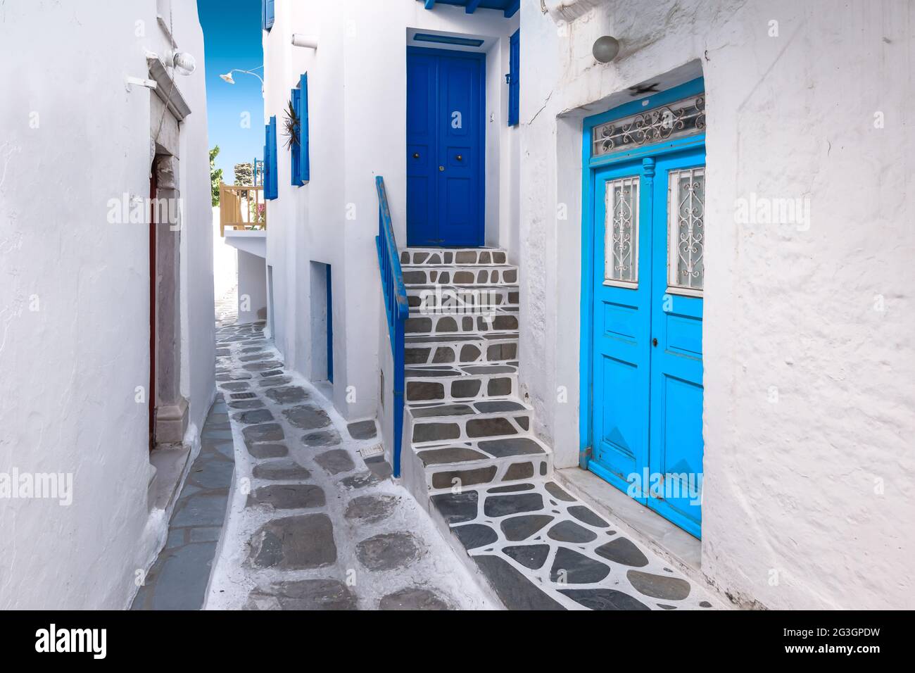 Traditional greek house with blue door and staircase in narrow city alley. Mykonos Island, Greece. Stock Photo