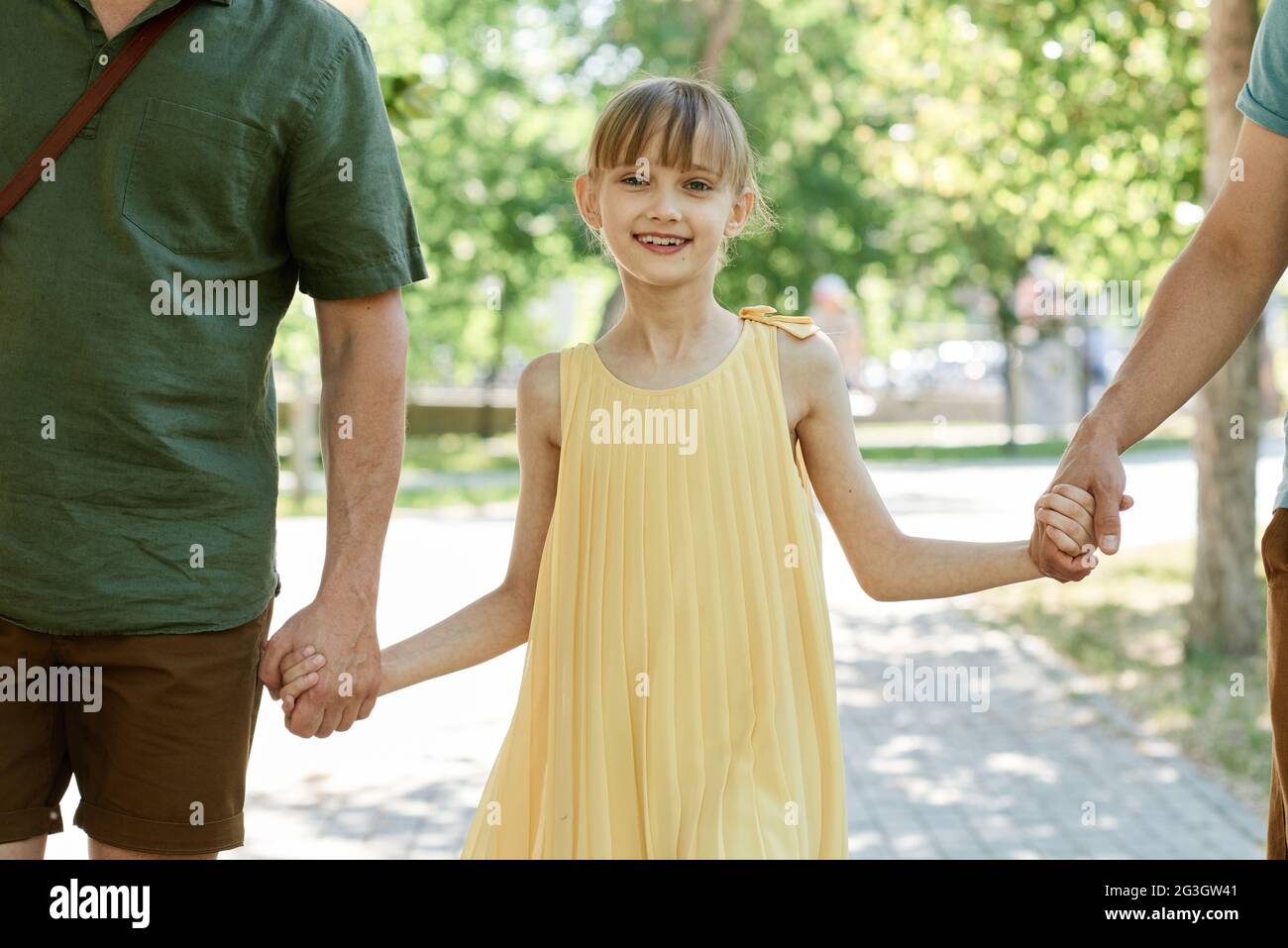 Portrait of little girl smiling at camera while walking in the park together with her family Stock Photo