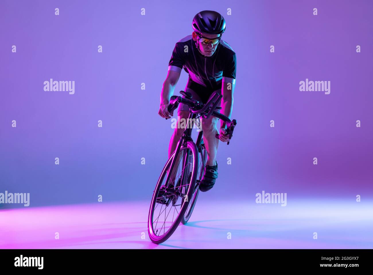 Cyclist riding a bicycle isolated against neon background Stock Photo