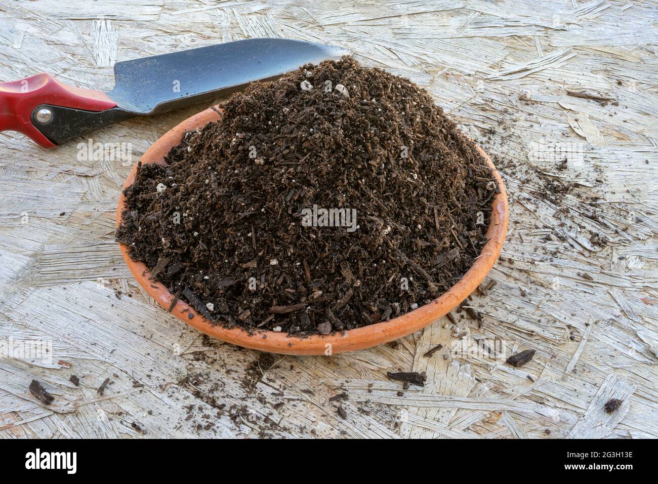 Potting  soil sample on a terra cotta dish with a hand shovel Stock Photo