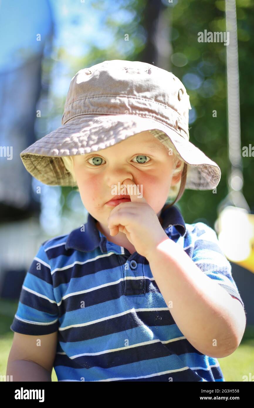 Adorable blonde Australian kid picking his nose in the playground Stock