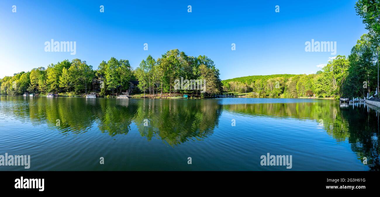 Scenic panorama of Lake Dartmoor in Tennessee shows a very calm, glassy lake surface with rich, healthy oak trees lining the shoreline. Stock Photo