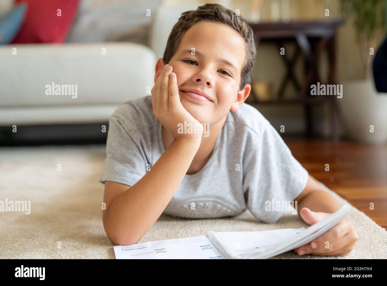 Cute little boy reading a book while lying on the floor Stock Photo - Alamy