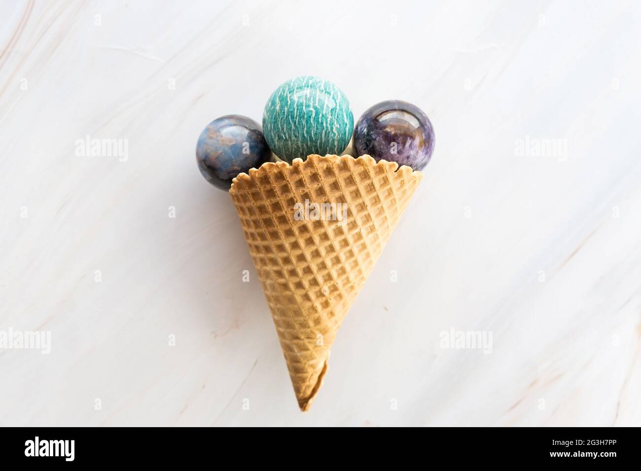Ice cream cone with round crystal stones on marble background as an