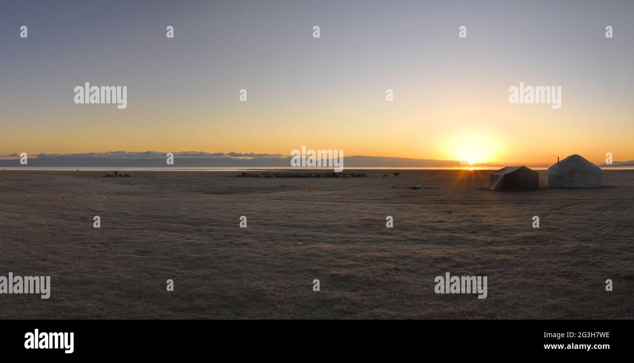 Scenic panorama of sunset on green grasslands in Kyrgyzstan with traditional namodic yurt Stock Photo