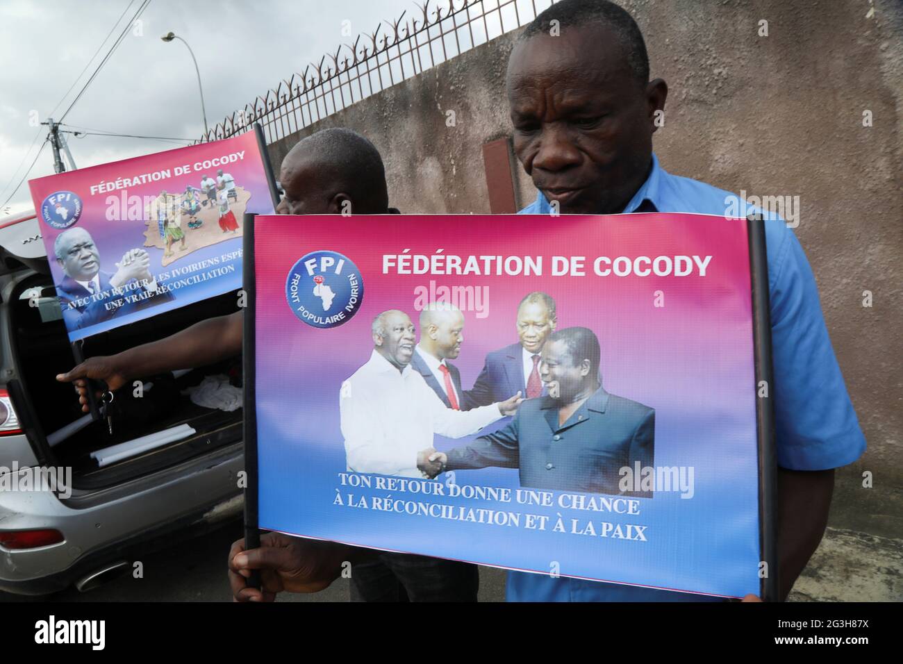 A Supporter Of Former Ivorian President Laurent Gbagbo Holds A Poster Showing Him Shaking Hands With Former Ivorian President Henri Konan Bedie And Ivorian President Alassane Ouattara Talking With The Former Leader A Supporter Of Former Ivorian President Laurent Gbagbo Holds A Poster Showing Him Shaking Hands With Former Ivorian President Henri Konan Bedie And Ivorian President Alassane Ouattara Talking With The Former Leader