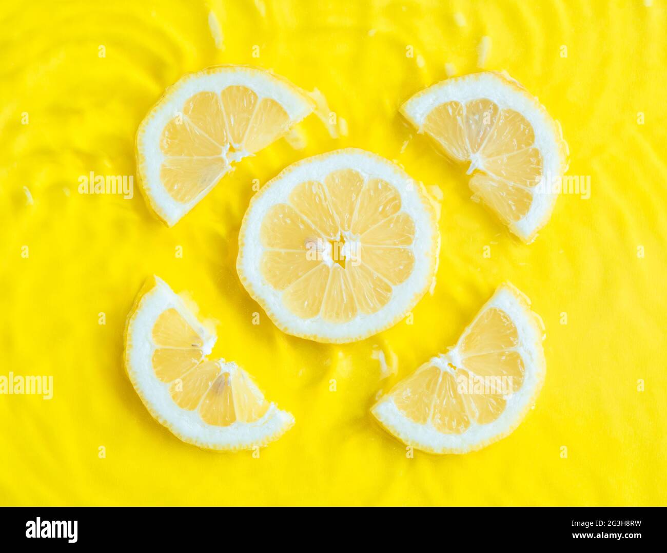 Intense yellow lemon citrus slice in water with ripples texture summer ...