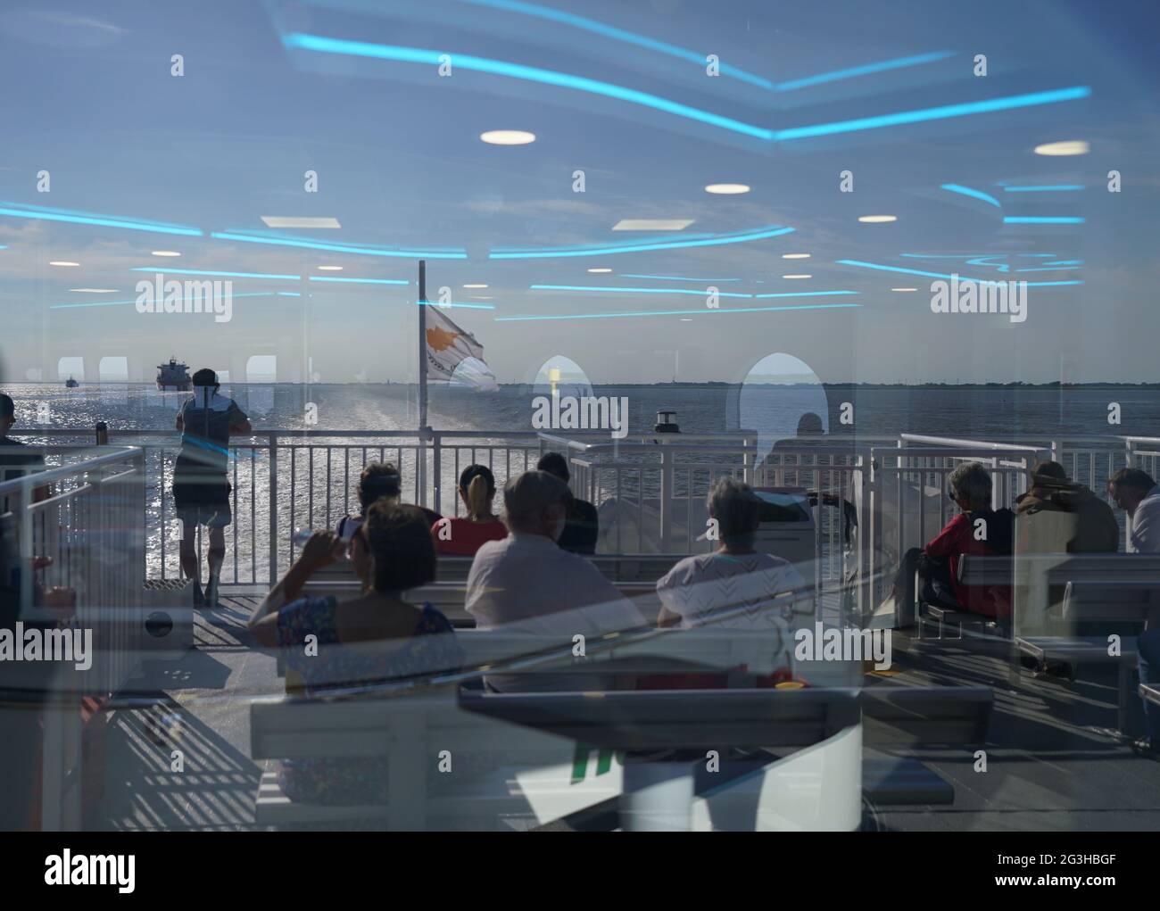 16 June 2021, Schleswig-Holstein, Brunsbüttel: Ships on the Elbe and passengers are reflected in a pane on the outer deck of the Helgoland ferry 'Halunder Jet'. Photo: Marcus Brandt/dpa Stock Photo