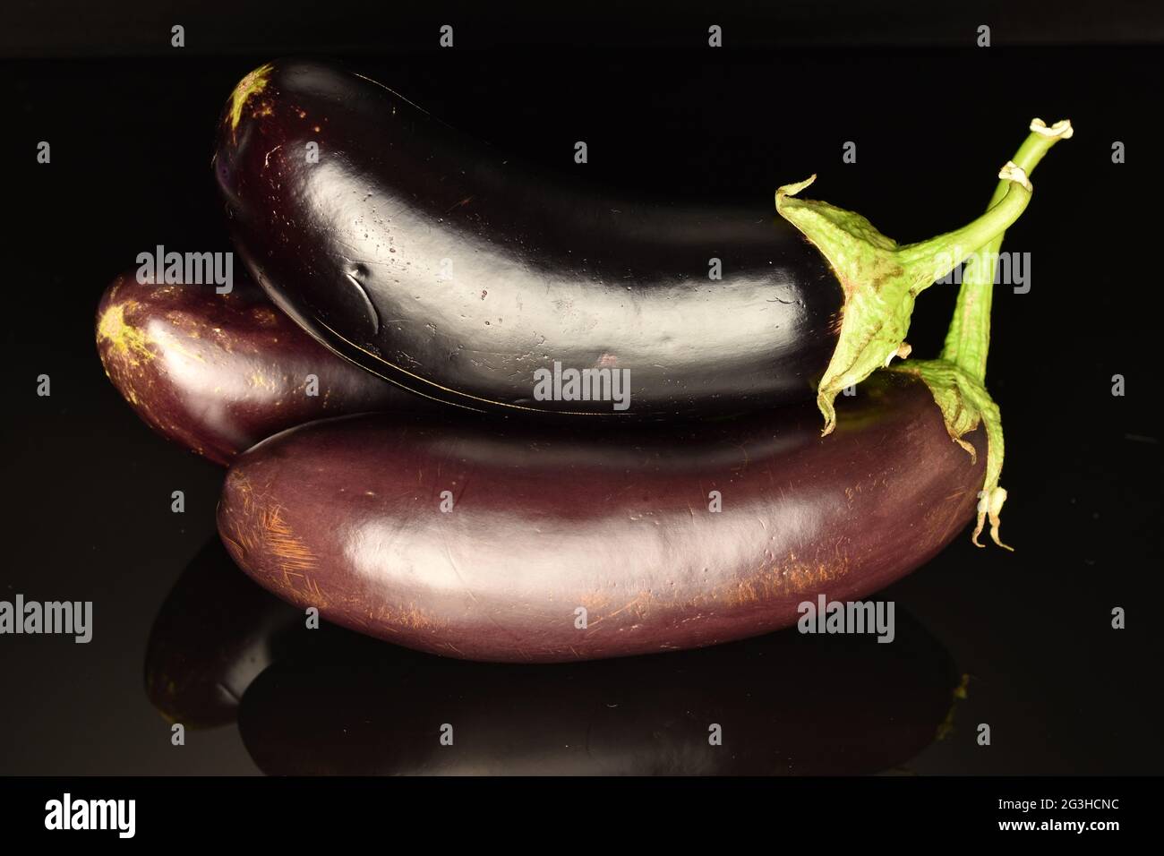 Several ripe dark eggplant, close-up, on a black background. Stock Photo