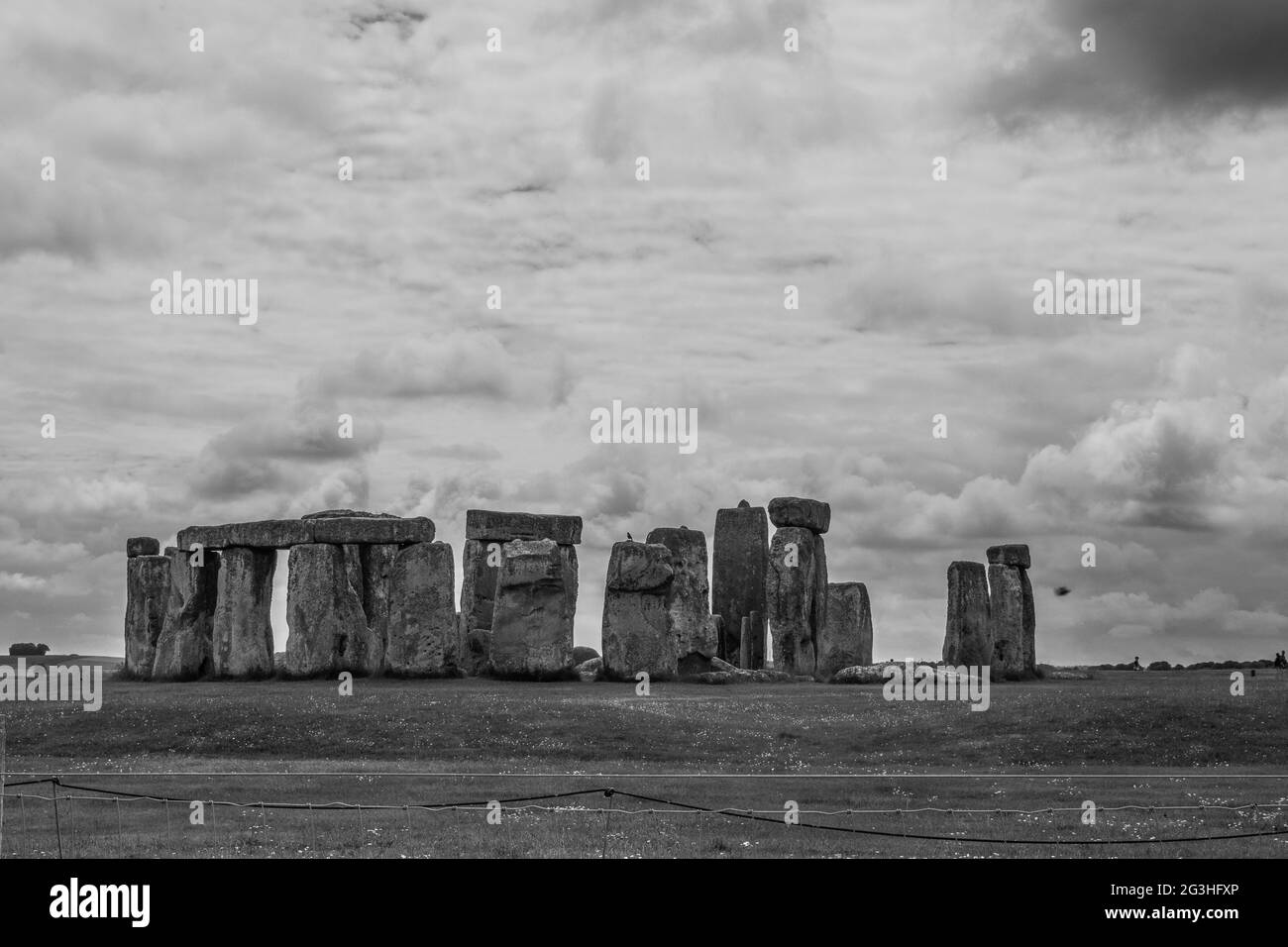 Black and white photo of the mystical stones of Stonehenge on a cloudy day with crows sitting on the stones Stock Photo