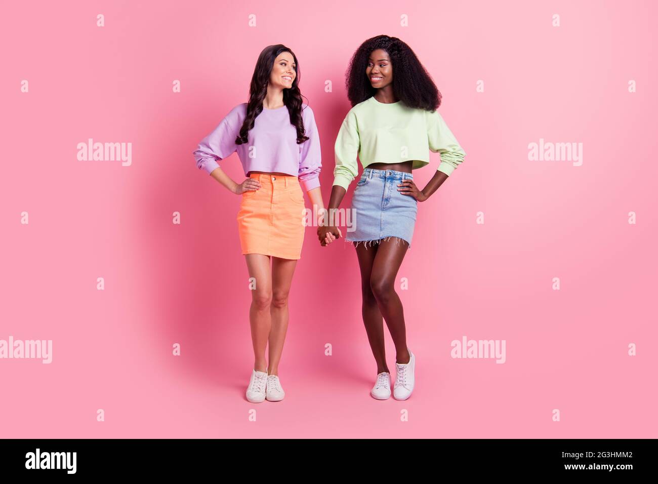 Full size photo of cute ladies wear cropped sweater mini skirt hold hands  isolated on pastel pink color background Stock Photo - Alamy