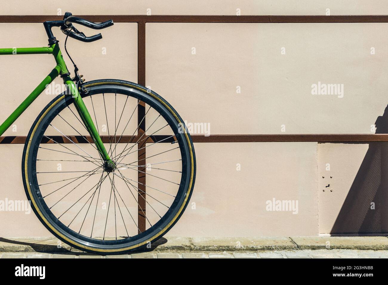 closeup of the front wheel of an old bicycle leaning on a railing of a