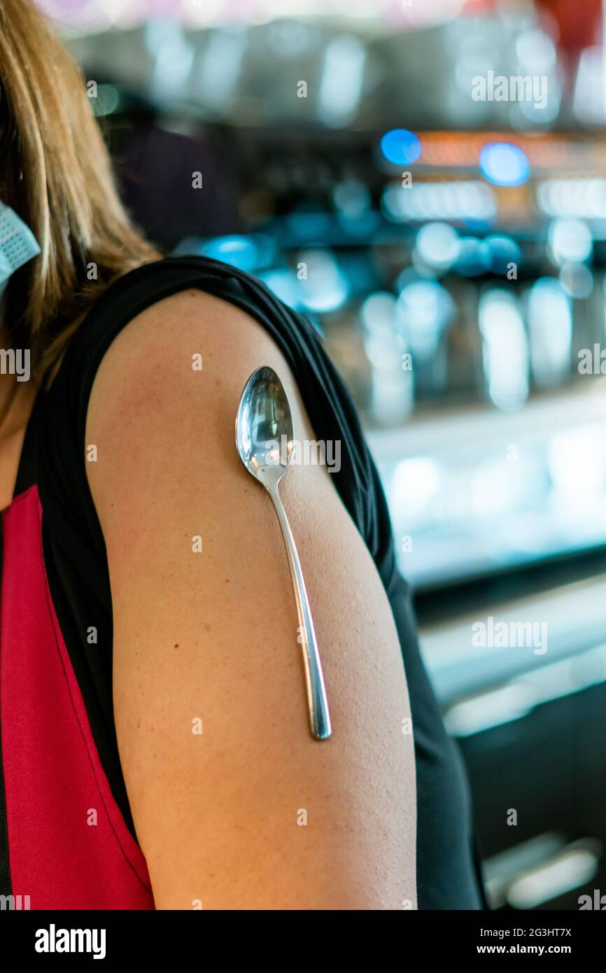 Spoon on a woman's arm for the lie that the covid vaccine attracts metal objects Stock Photo