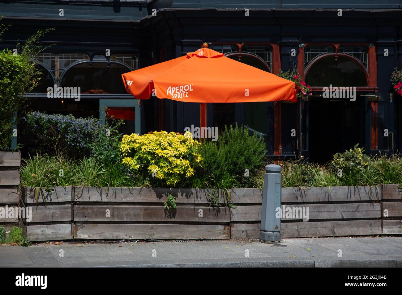 A bright orange Aperol Spritz parasol in a pub garden in Hammersmith, London, UK Stock Photo