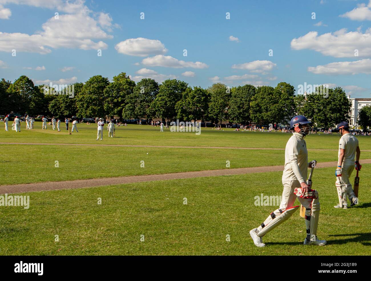 Amateur cricket match on Richmond Green, a recreation area in Richmond, Surrey, UK; one cricketer is out and leaving the field Stock Photo