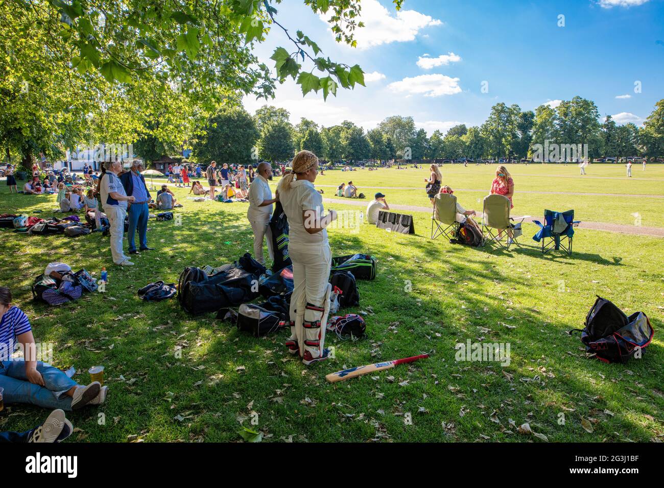 Amateur cricket match on Richmond Green, in Richmond, Surrey, UK; the team in whites preparing to go out to bat, including a woman cricketer Stock Photo