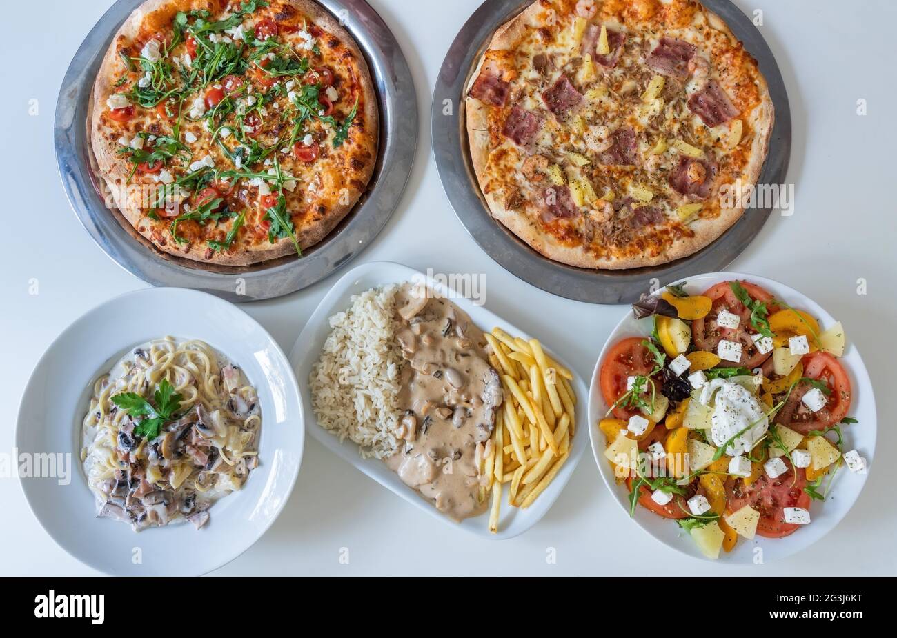 Variety of different cultural dishes in table of Indian food plates Pizza,salad, rice, meat, vegetables. Food panorama. Top view Stock Photo