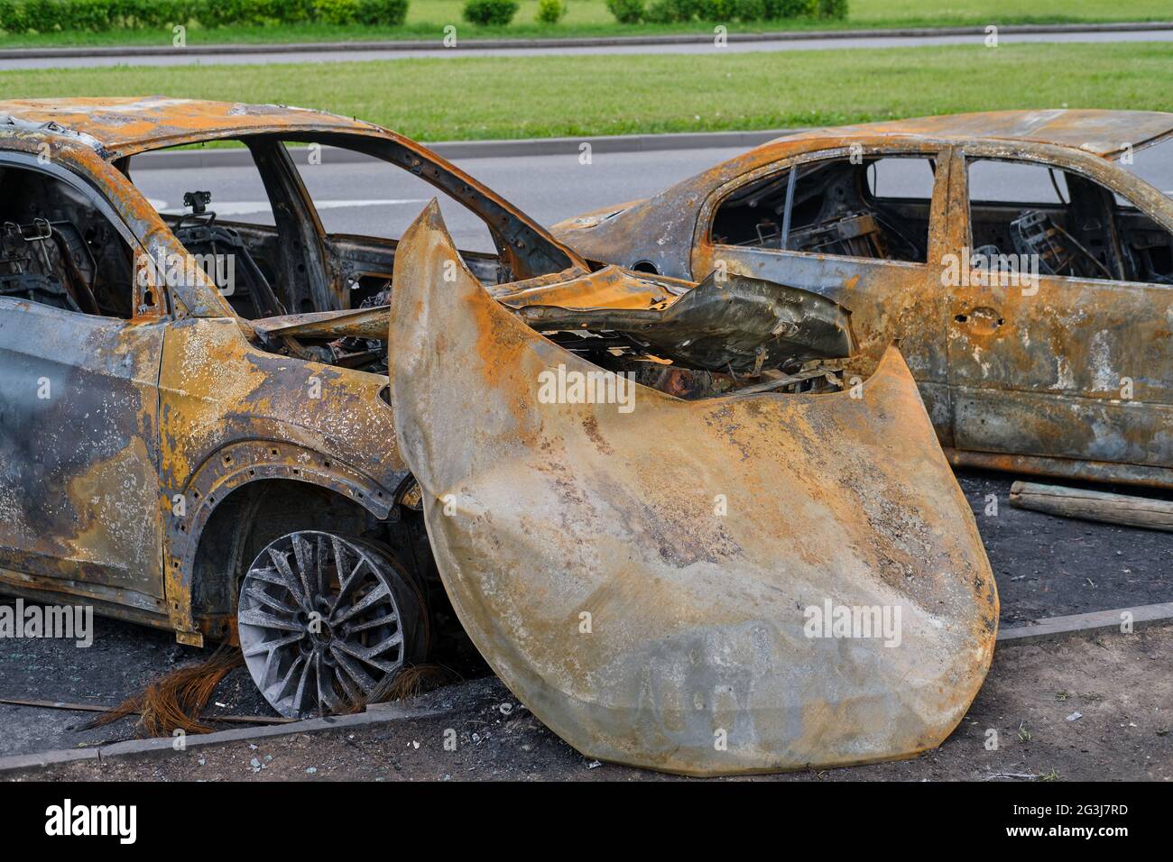 Burnt-out rusty cars on a city street, vandalism. Setting fire to 