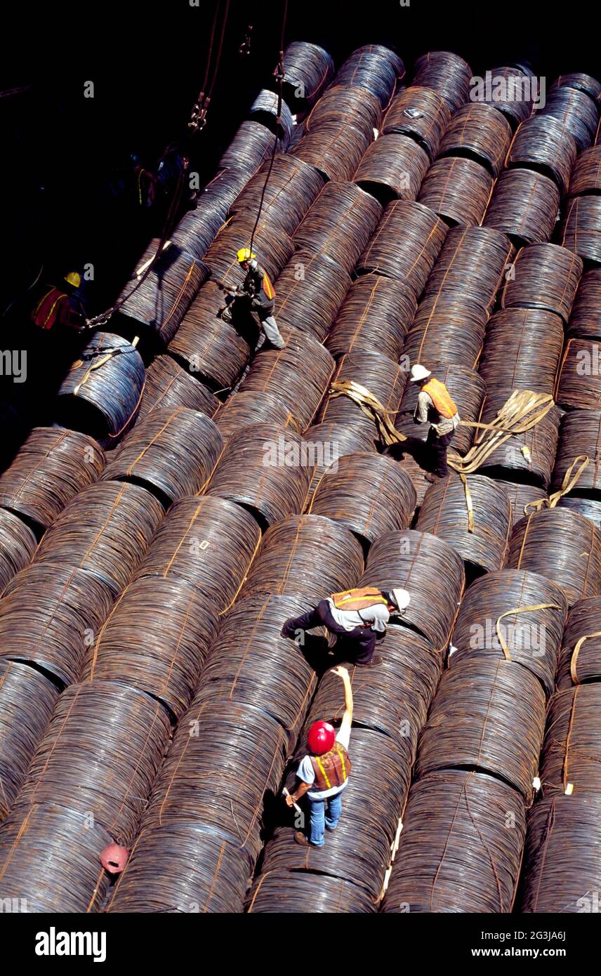 steel products (coiled wire rod) in the cargo hold. Tally checks the coils one by one while unloading Stock Photo