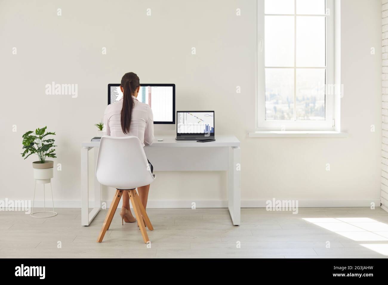 Back view of focused girl sitting at home office desk working at