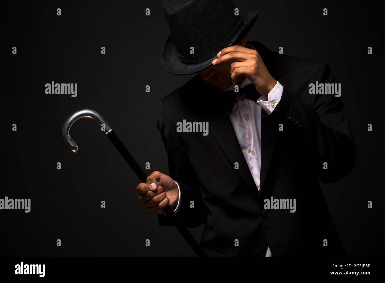 Handsome man in top hat posing with cane Stock Photo