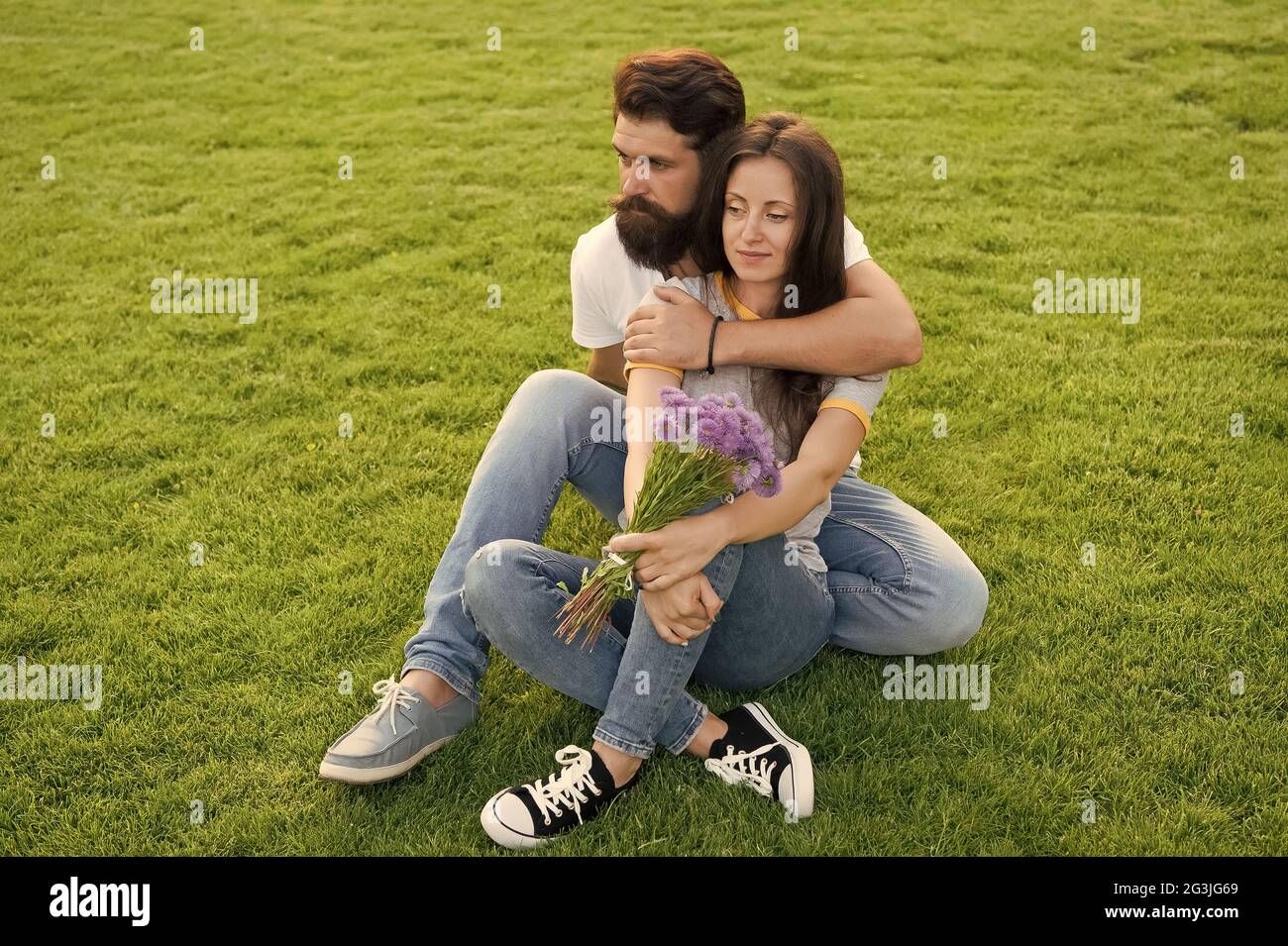 During outdoor recreational activities. Couple in love sit on green