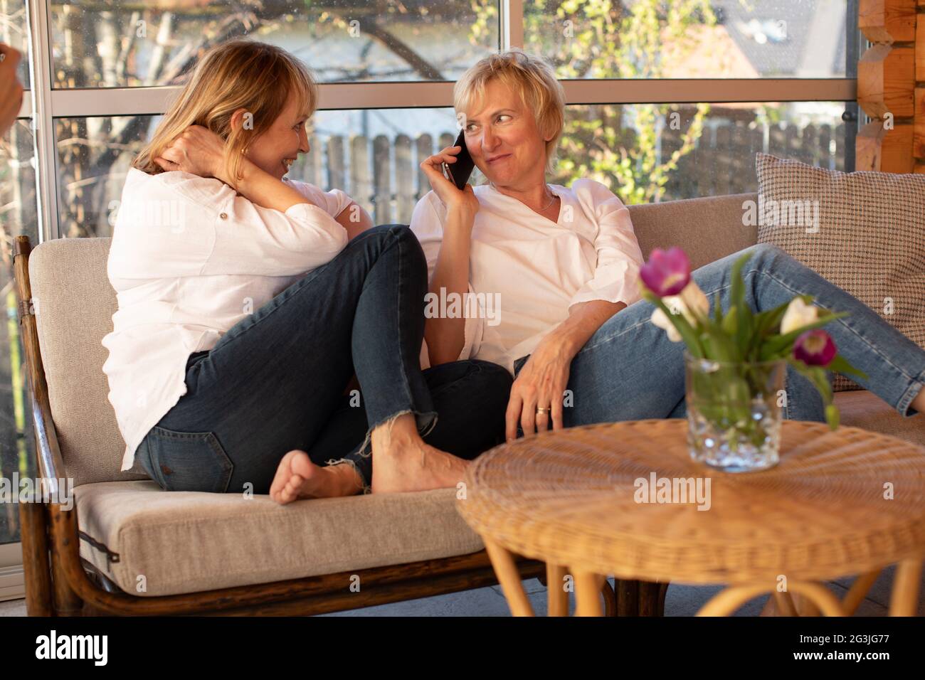 Two 55yearold women in casual clothes use smartphone to make call