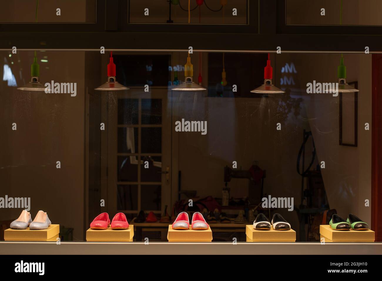 Shoes in a window display of a shoemaker workshop at night. A cobbler sewing machine is visible in the background. Stock Photo