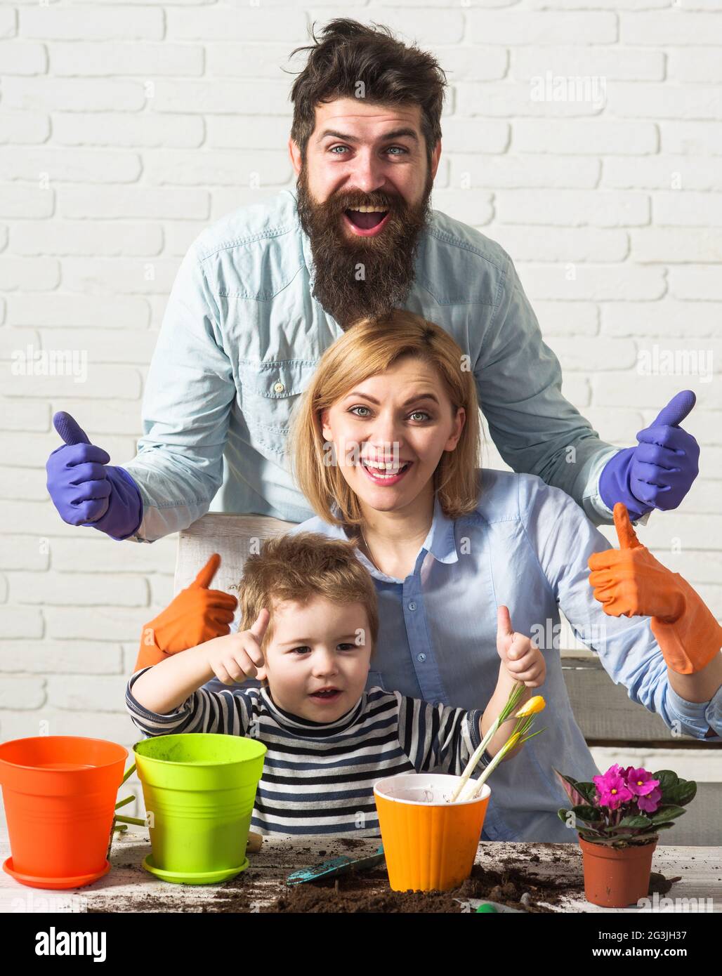 Family planting flowers together. Son helps parents to care for plants