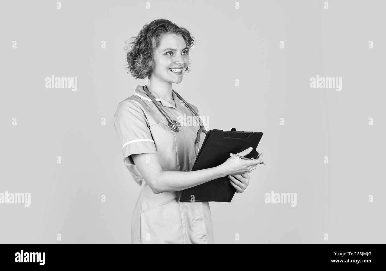ordinary working day. Smiling female doctor with a folder in uniform standing. Portrait of lovely nurse with a folder. She is wearing a stethoscope Stock Photo