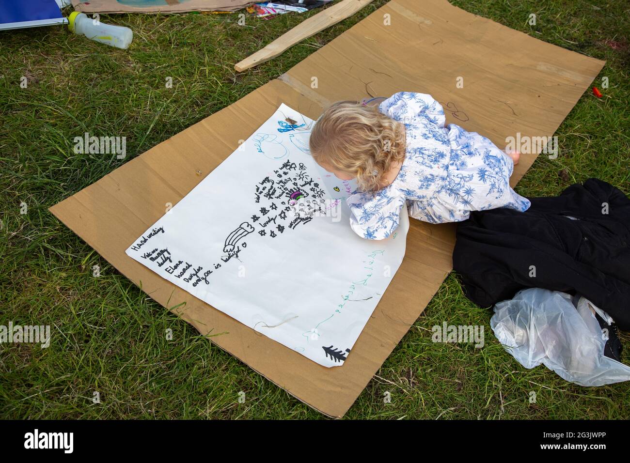 A little girl drawing a protest sign at the freedom protester camp on Shepherd's Bush Green, London, UK. June 2021 Stock Photo