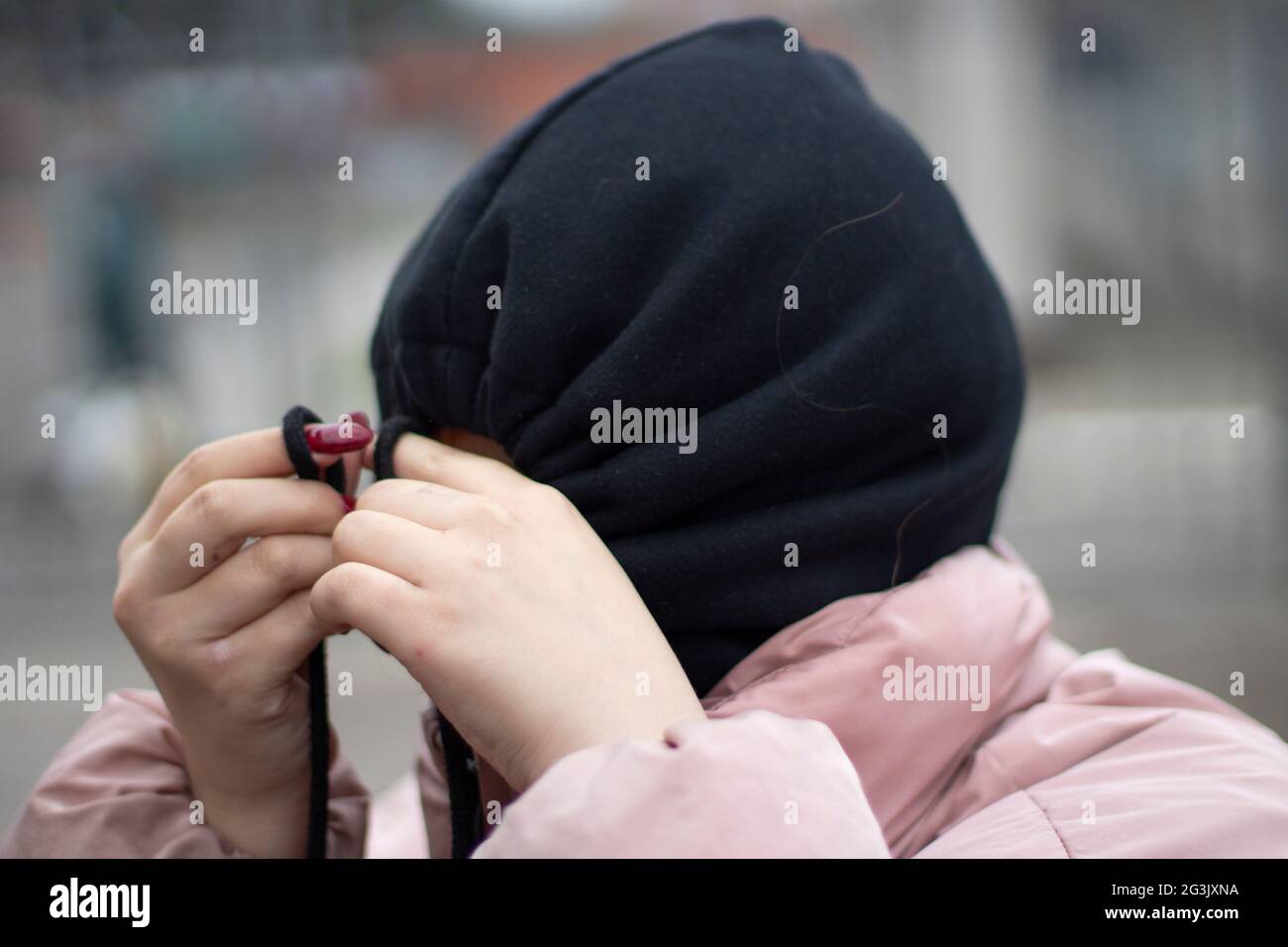 The girl hid in the hood. Girl in a black hood. The schoolgirl hid from people. Self-rejection. The man is depressed. Reluctance to communicate. Stock Photo