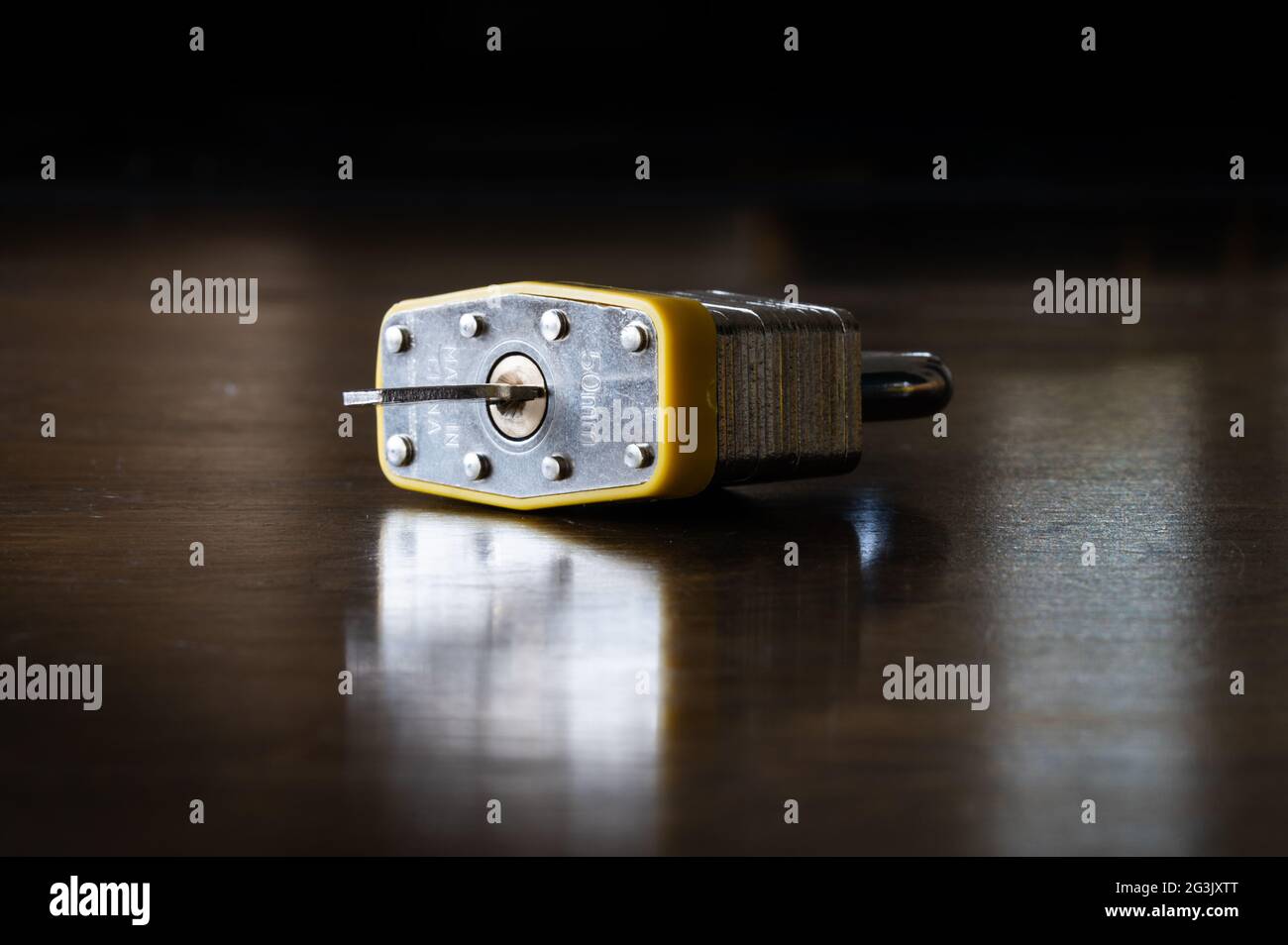 Padlock with Key Sitting on a Wood Table Stock Photo
