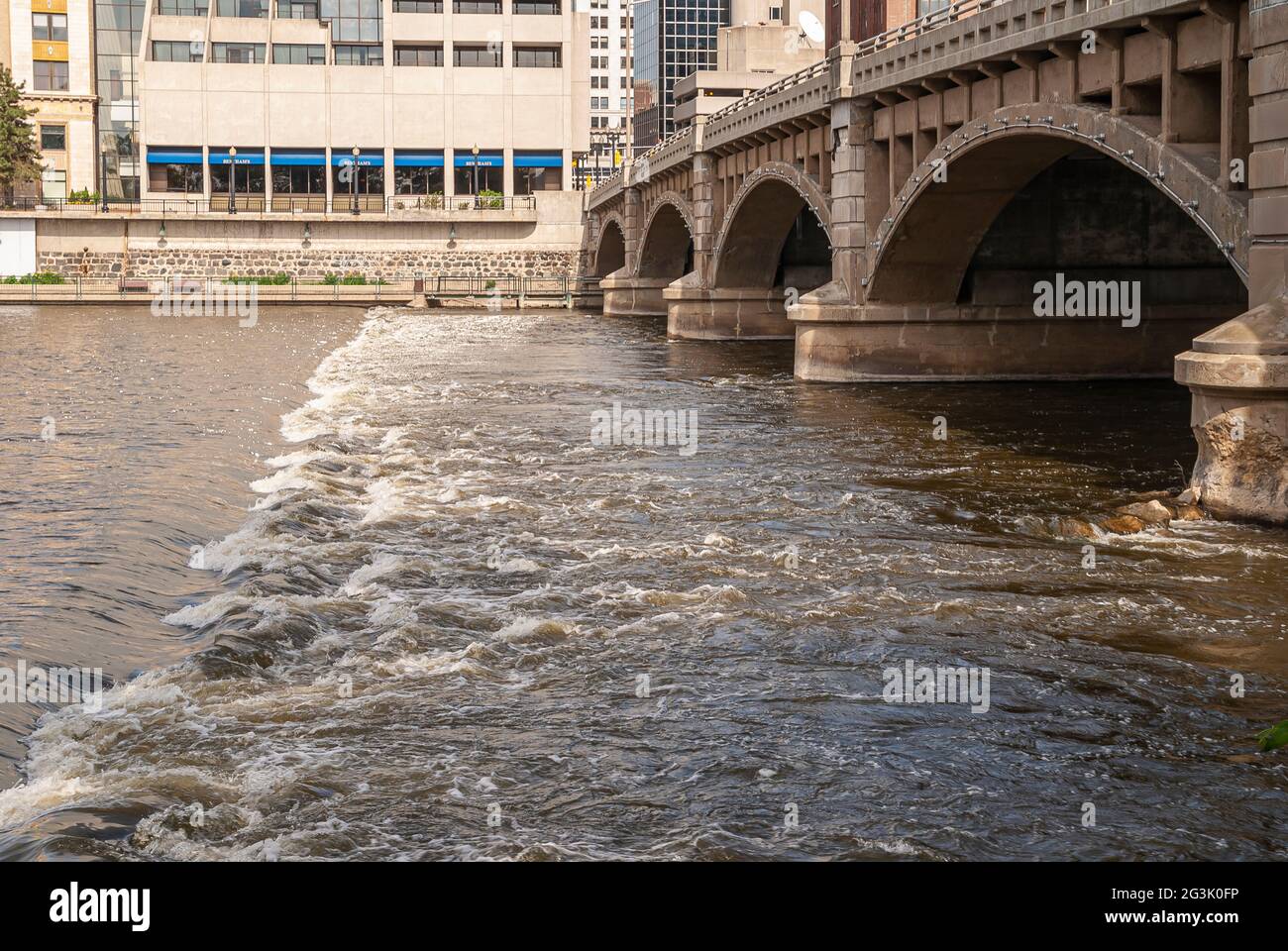 Grand Rapids, MI, USA - June 7, 2008: Rapid creating white foam in river just at Pearl Street NW arched bridge of which side is shown. Buildings acros Stock Photo
