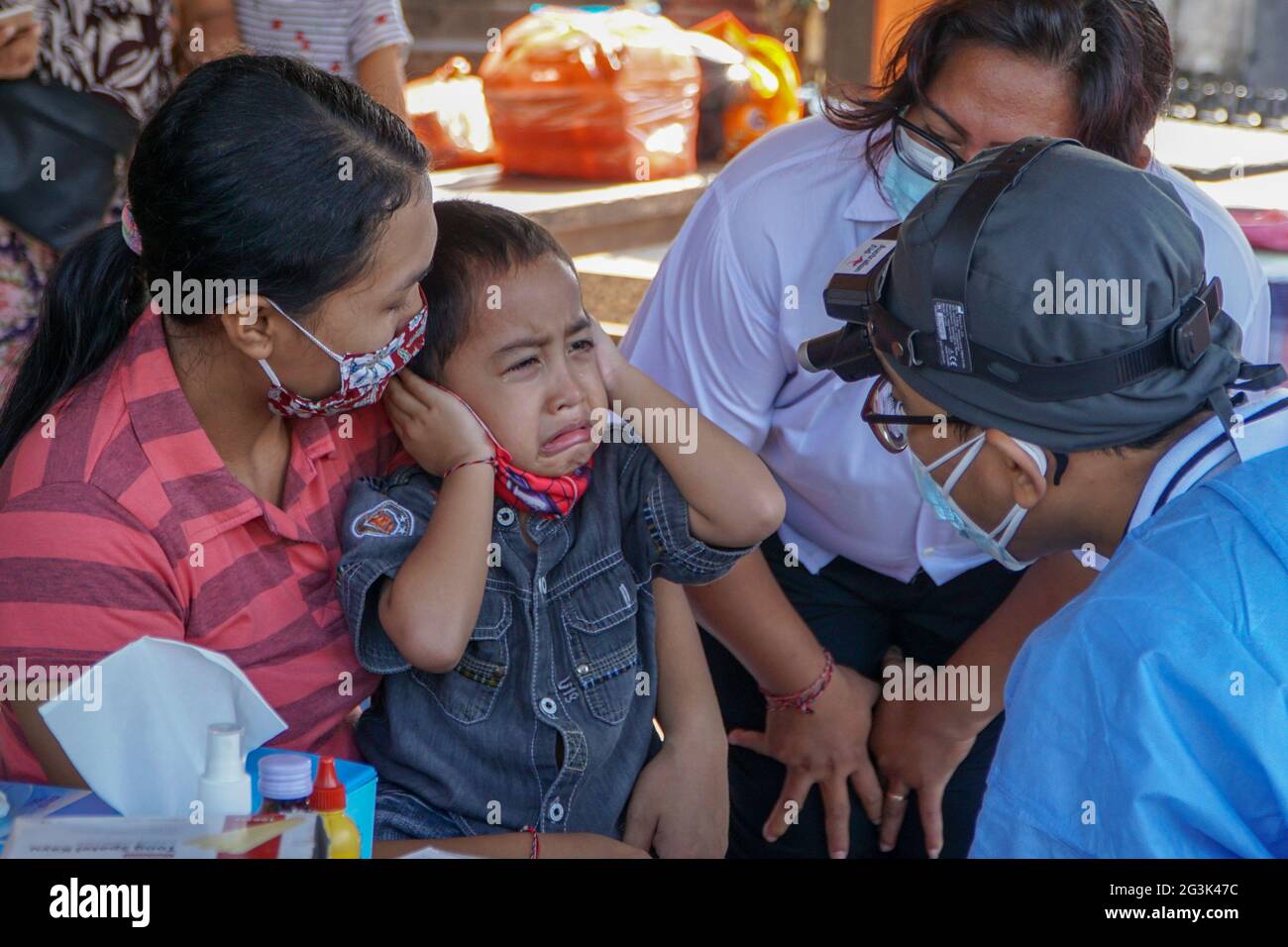 BALI/INDONESIA-MAY 28 2021: An ENT doctor is examining the ears, nose and throat of a pediatric patient. During the COVID-19 pandemic, ENT examination Stock Photo