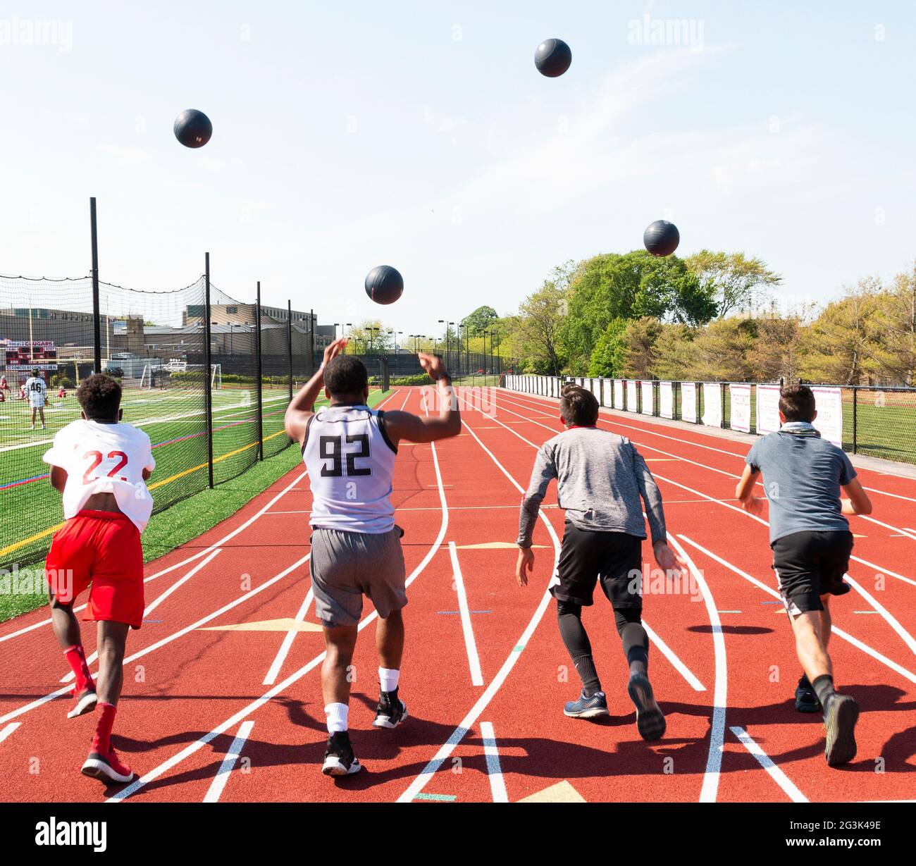 Rear view of four track athletes throwing medicine balls high in the