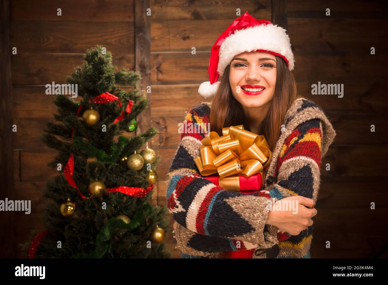 Beautiful girl hugging a present near New Year tree Stock Photo - Alamy