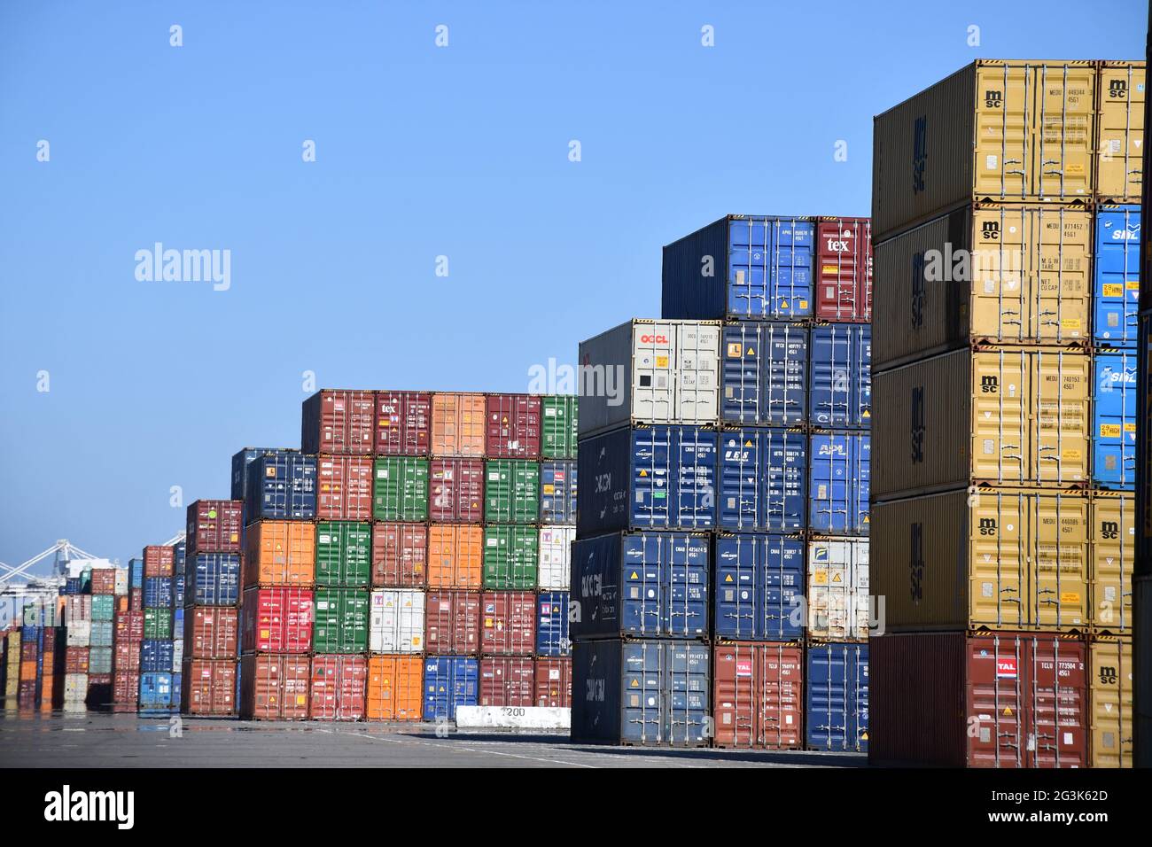 Shipping containers are loaded onto ships at the Port of Oakland, California, one of the busiest global freight ports on the West Coast. Stock Photo