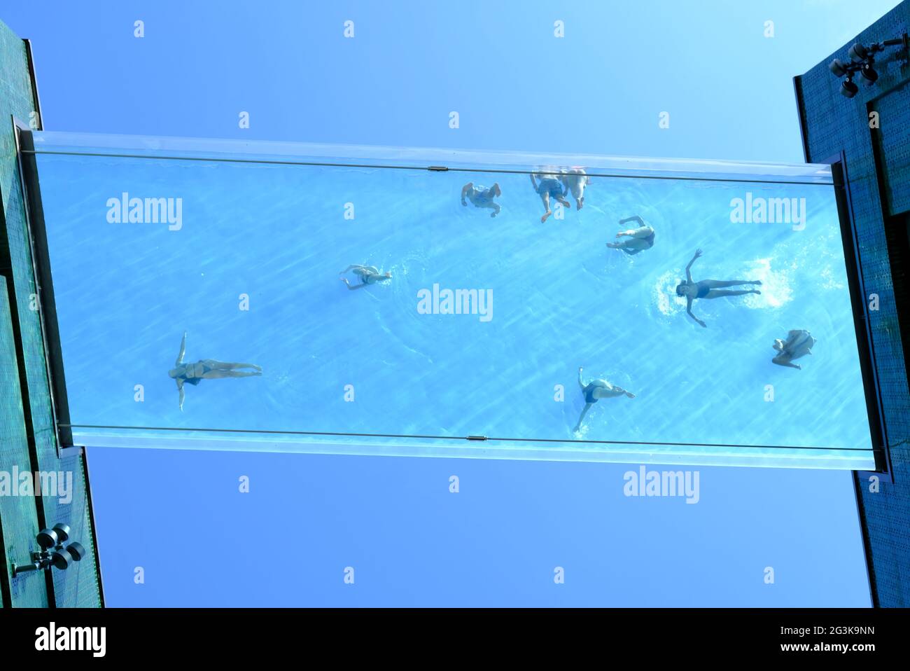 London, UK Looking up at the transparent Sky Pool at Embassy Gardens where residents are enjoying swimming on a sunny day 115ft up in the air. Stock Photo