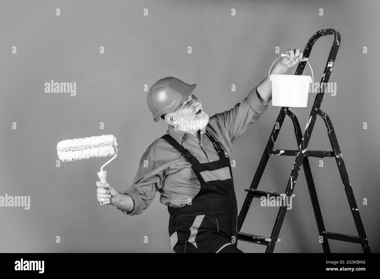 working in repair shop. senior man painter use roller on ladder